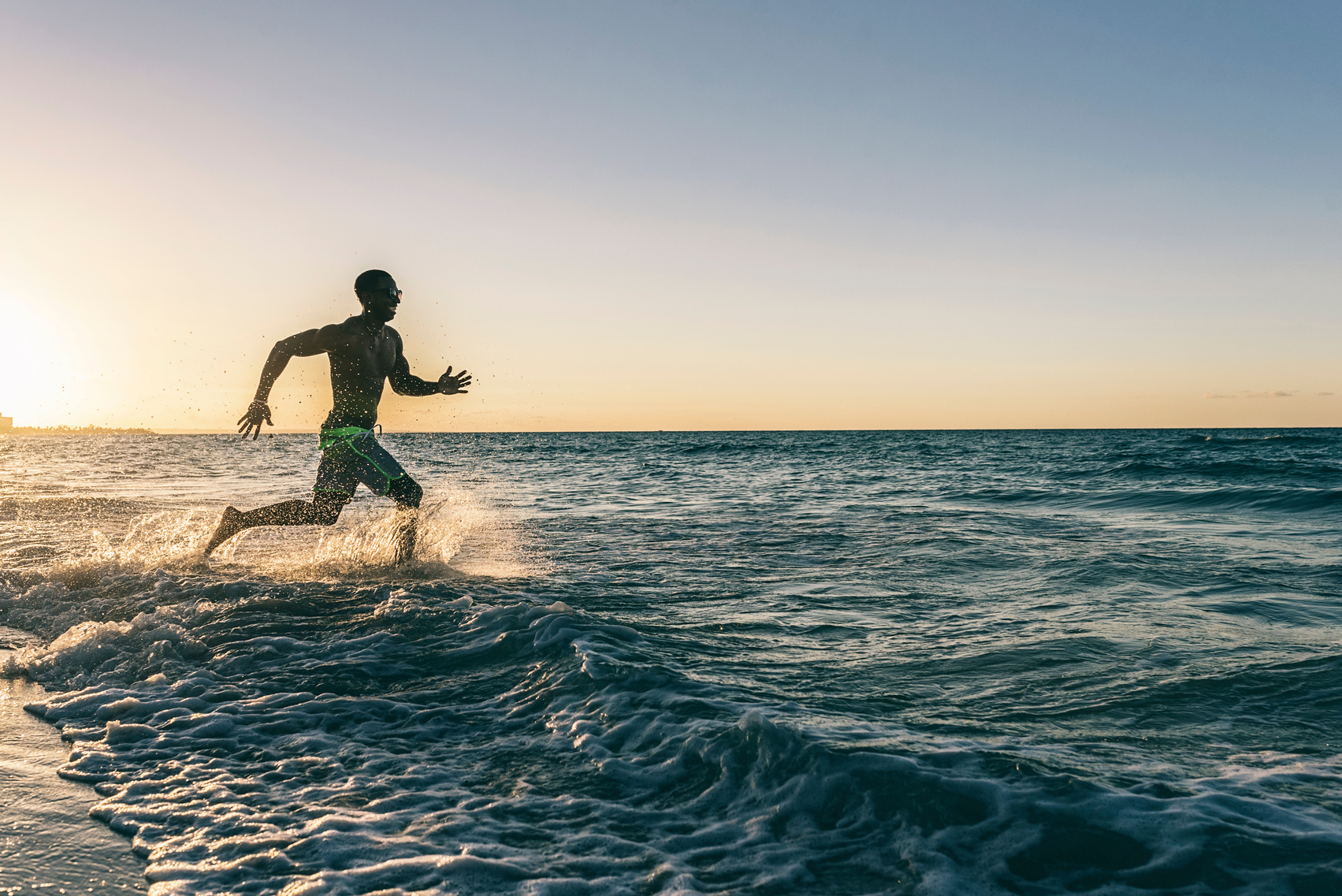 Young man running into the beach. Happy attitude.